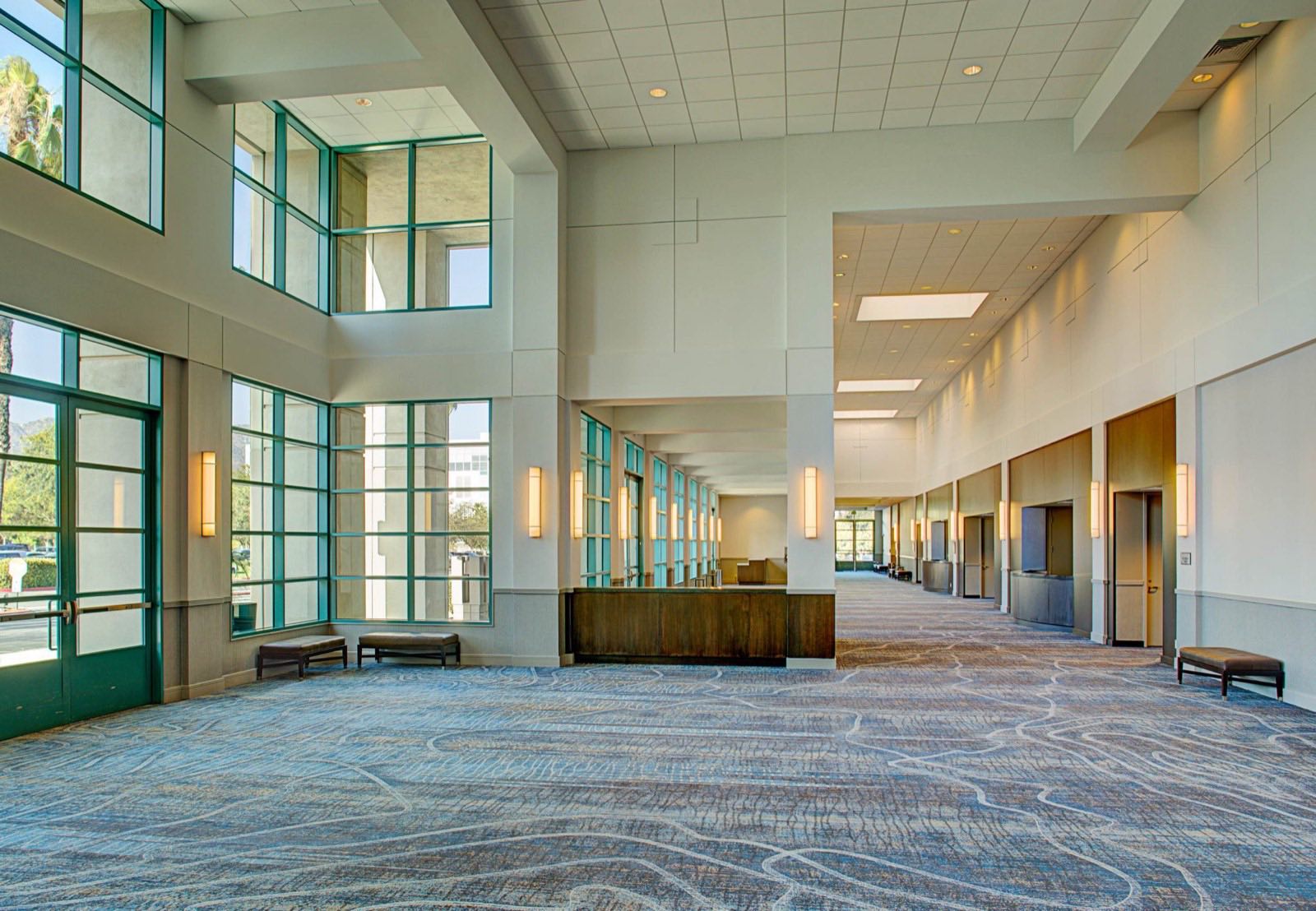 Sunlit convention center foyer with two-story glass walls